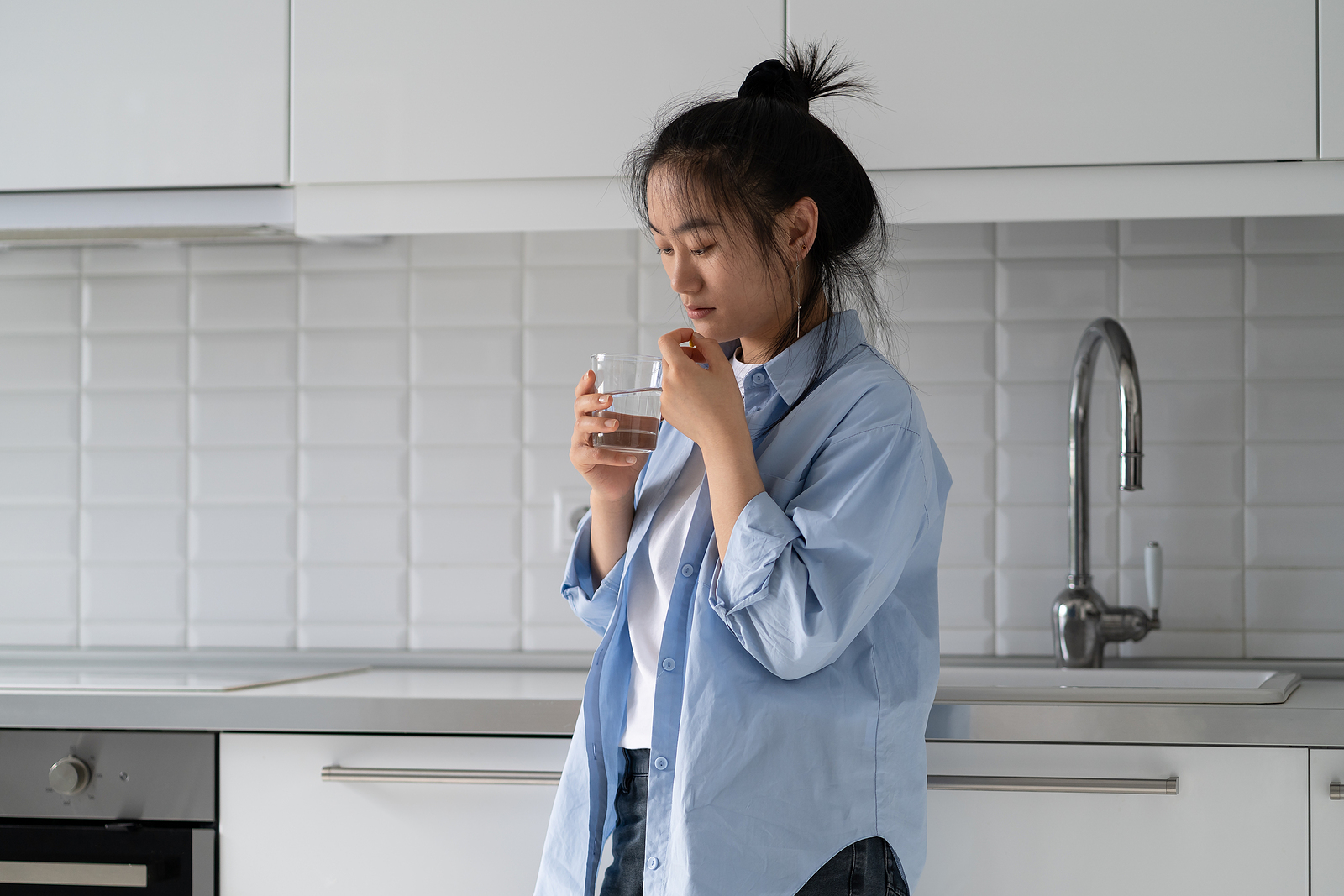 Thoughtful Emotionless Asian Woman Taking Hormone Pills And Drin
